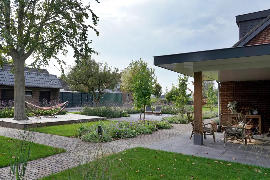 Moderne overkapping aan het huis met loungeset en uitzicht op de tuin