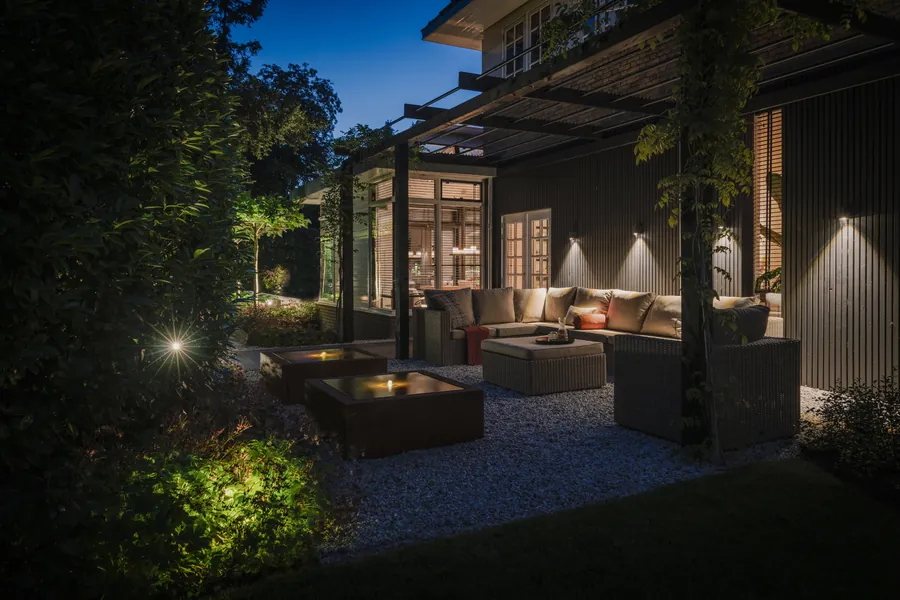 Loungeplek met tuinverlichting en ingebouwde vuurtafels bij avond