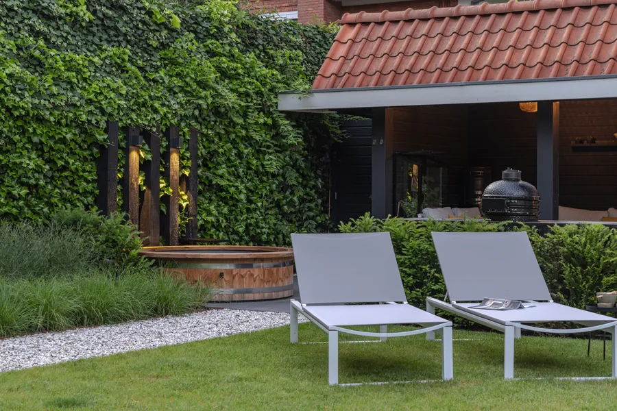 Houtgestookte hottub in een strakke tuin met ligbedden