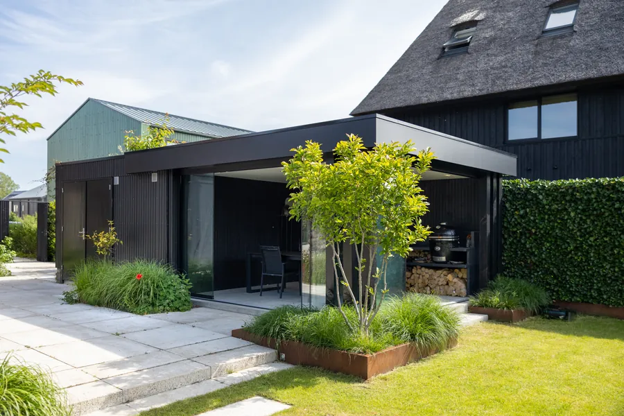 Zwart houten bijgebouw met buitenkeuken, gebouwd door Bax Hoveniers
