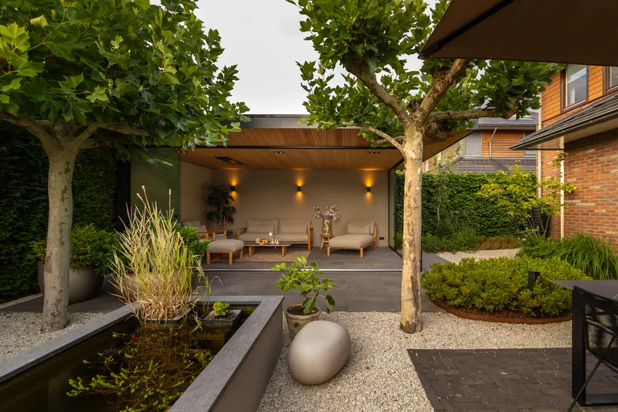 Zicht over de vijver op de verlichte tuinkamer